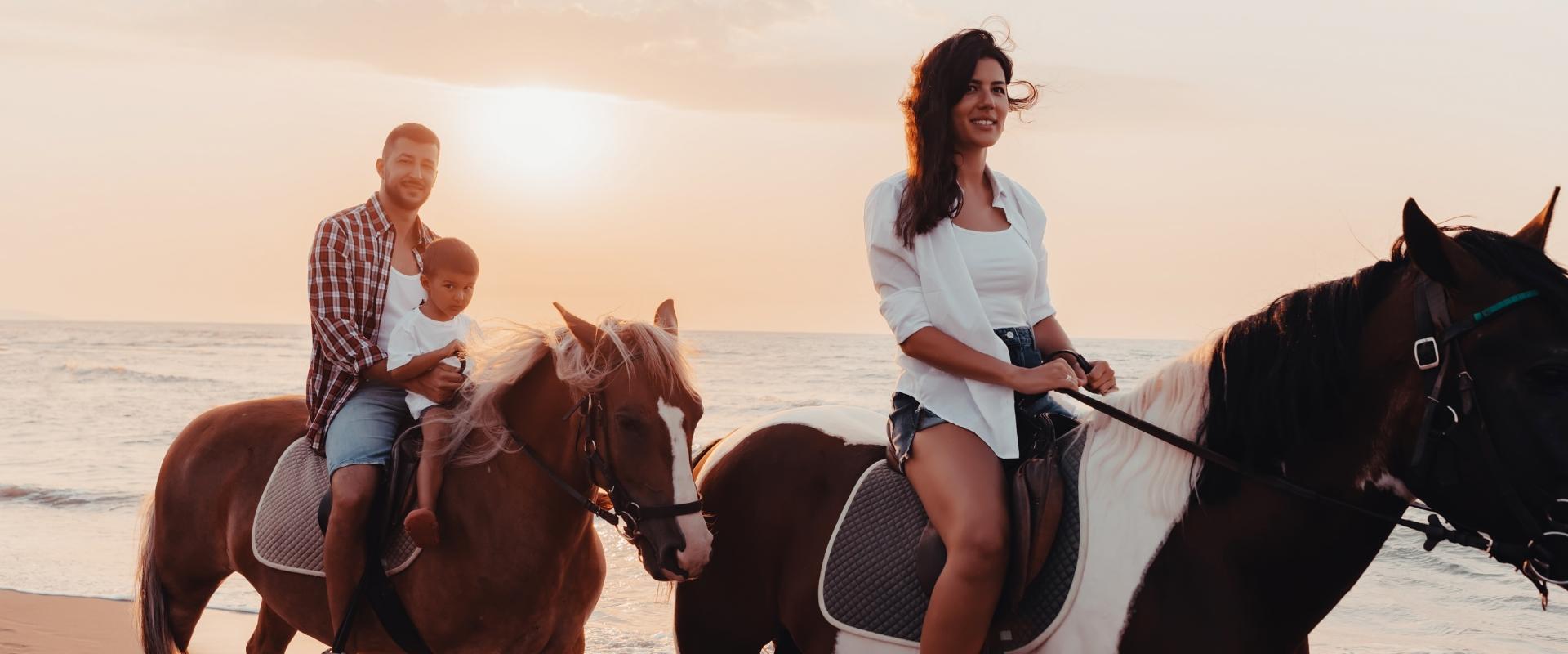 Famiglia a cavallo sulla spiaggia al tramonto, felici e rilassati.